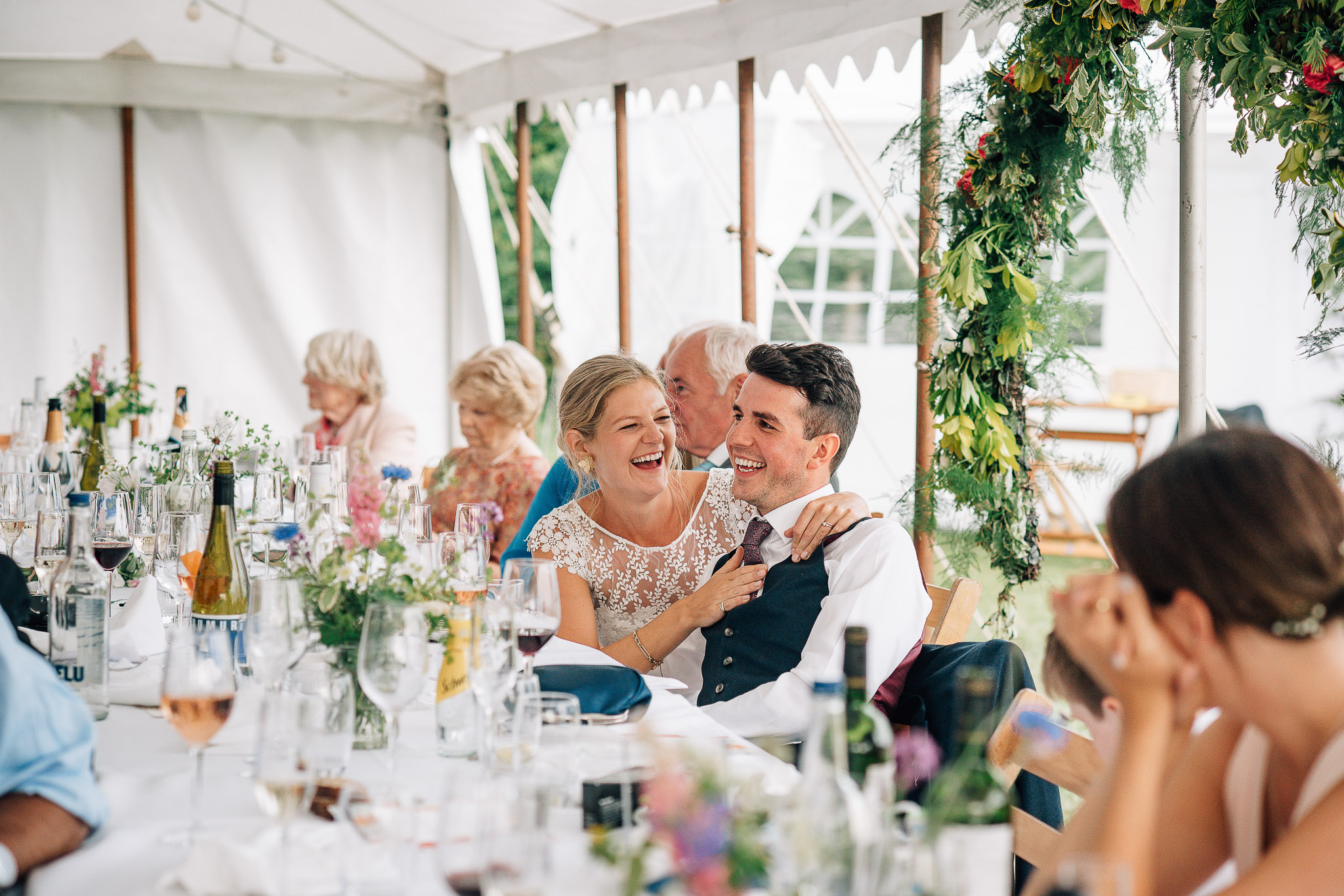 bride embracing and smiling at groom during wedding reception in marquee