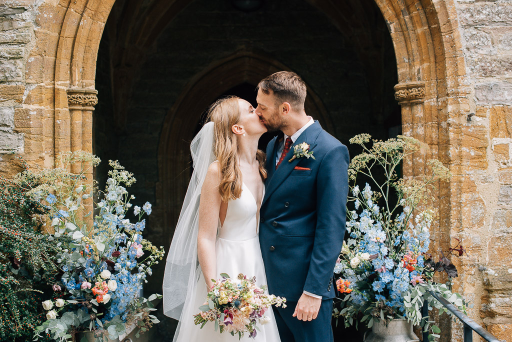 bride and groom kissing outside of church