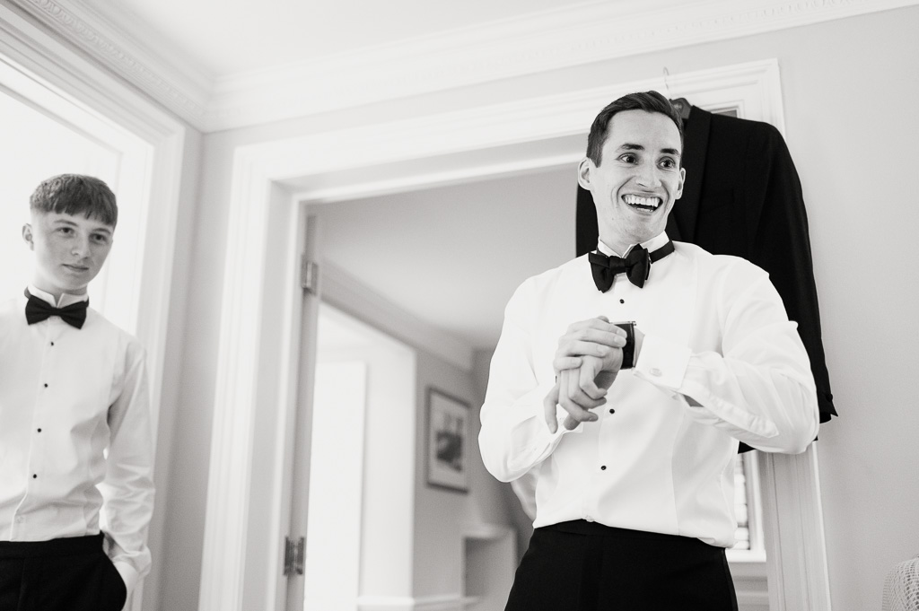 groom in black tie looking at the time and smiling before his wedding
